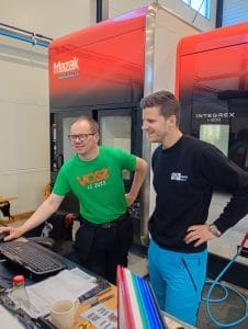 To menn fra Bjørgum mekaniske står og ser på en datamaskin. En mazak-maskin er synlig i bakgrunnen